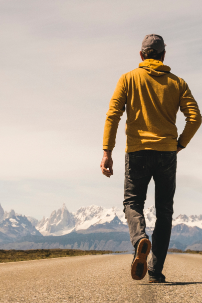 man walking towards mountains